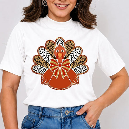 A woman wearing a white short-sleeve t-shirt with a graphic of a turkey made from leopard print and black-and-white spotted feathers, paired with blue jeans.