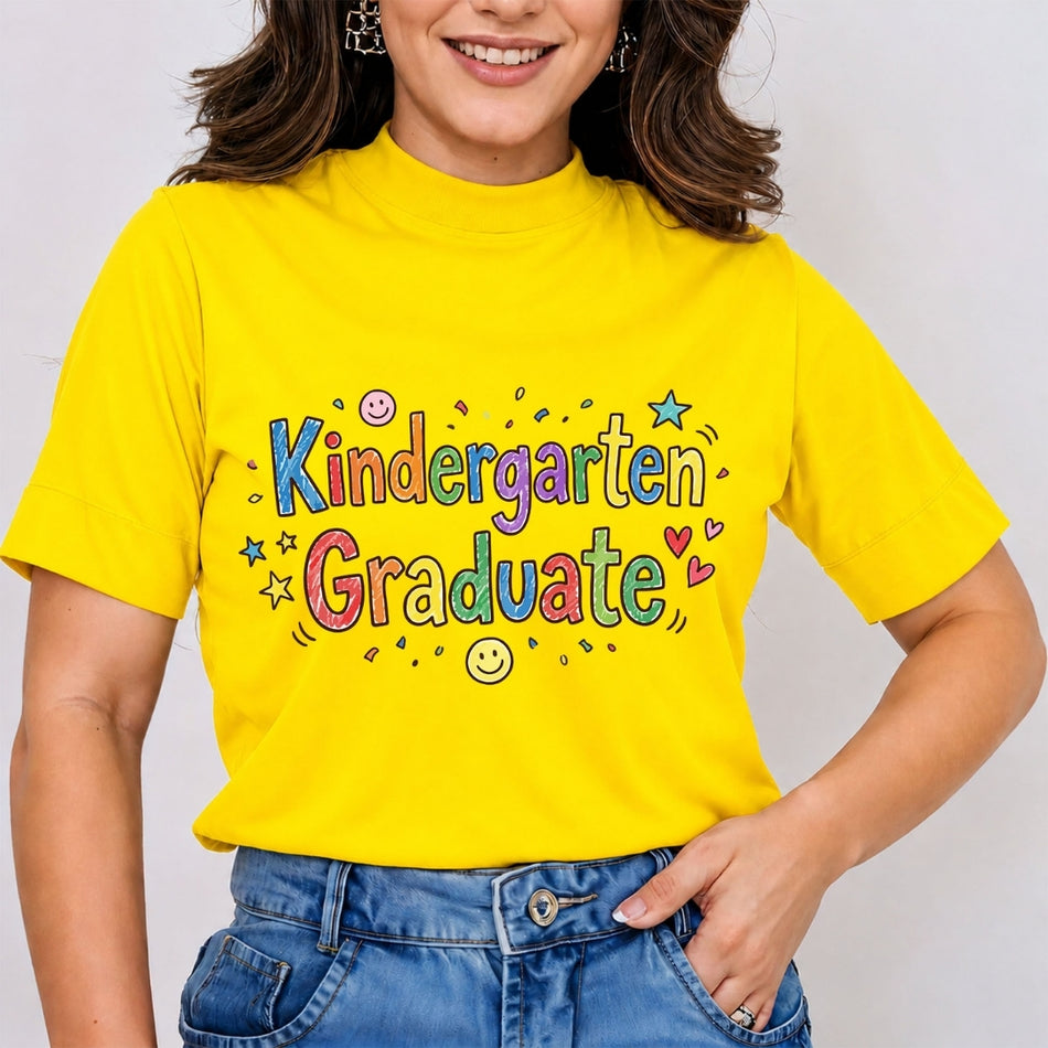 A woman wearing a bright yellow mock-neck t-shirt with a colorful 'Kindergarten Graduate' graphic on the front, paired with blue jeans.