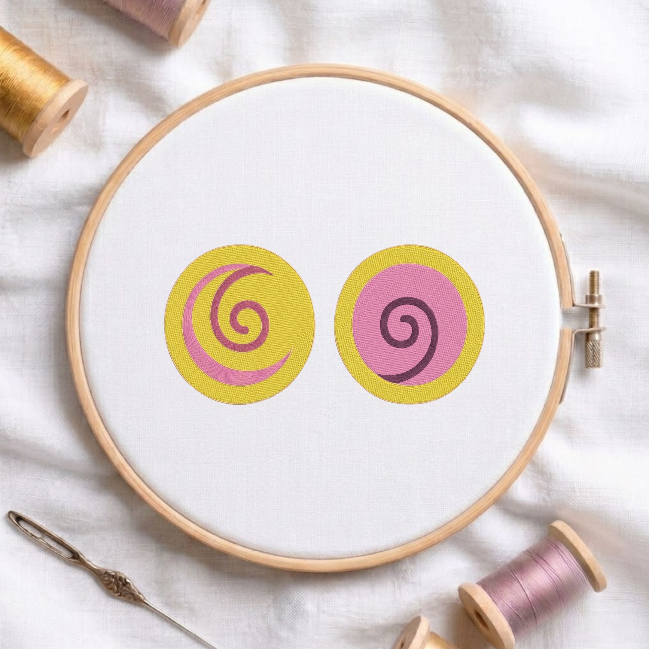 Yellow and pink spiral swirl circles embroidery pattern stretched in a round wooden hoop on white linen.
