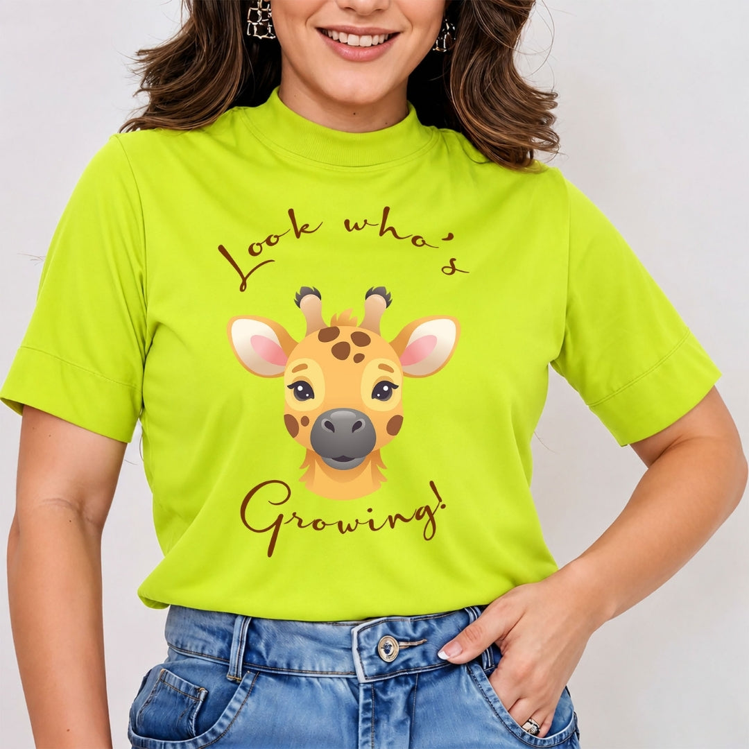 Woman wearing lime green mock neck t-shirt featuring a cute cartoon giraffe graphic with text reading Look Whos Growing.