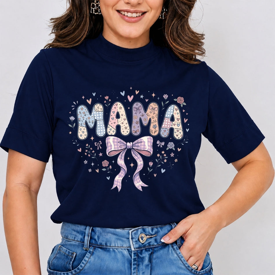 A woman wearing a navy blue short-sleeve t-shirt with a colorful graphic that reads 'MAMA' in patterned letters with a pink bow and hearts, paired with blue jeans.