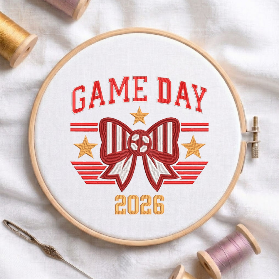 A close-up of the "GAME DAY 2026" design secured in a wooden embroidery hoop.