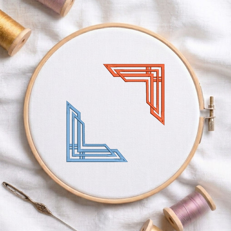 A wooden embroidery hoop holding white fabric, featuring two stylized geometric corner motifs in blue and orange. Surrounding the hoop are spools of thread in gold, pink, and peach, plus a metal needle on a soft white fabric background.