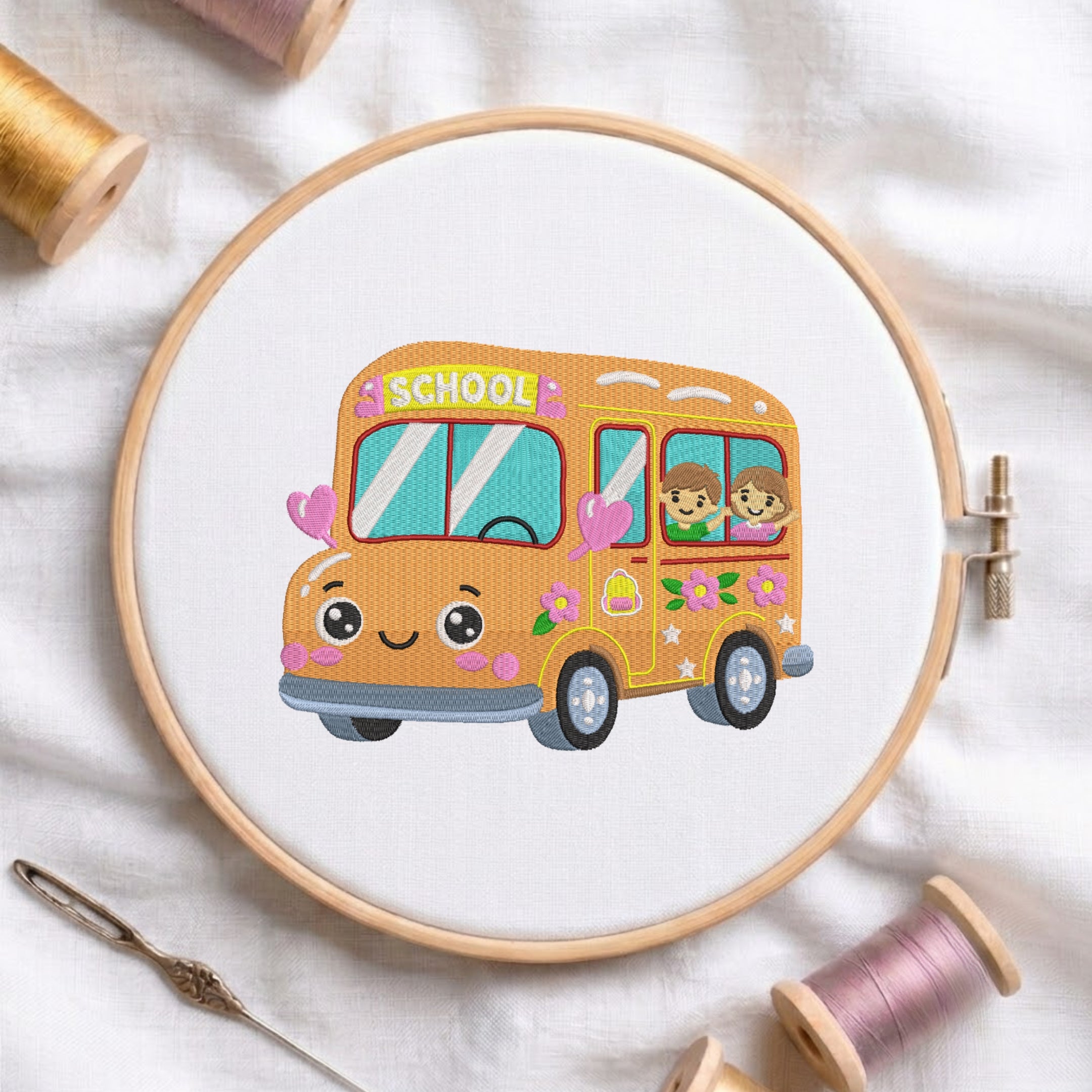 An embroidered design of a cheerful yellow school bus with cute eyes, pink hearts, and kids waving from the window, stitched inside a wooden hoop on white fabric with sewing threads.
