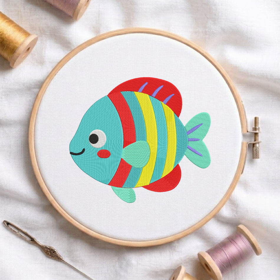 Cute colorful striped tropical fish embroidery design centered inside a wooden embroidery hoop on white fabric with spools of thread.