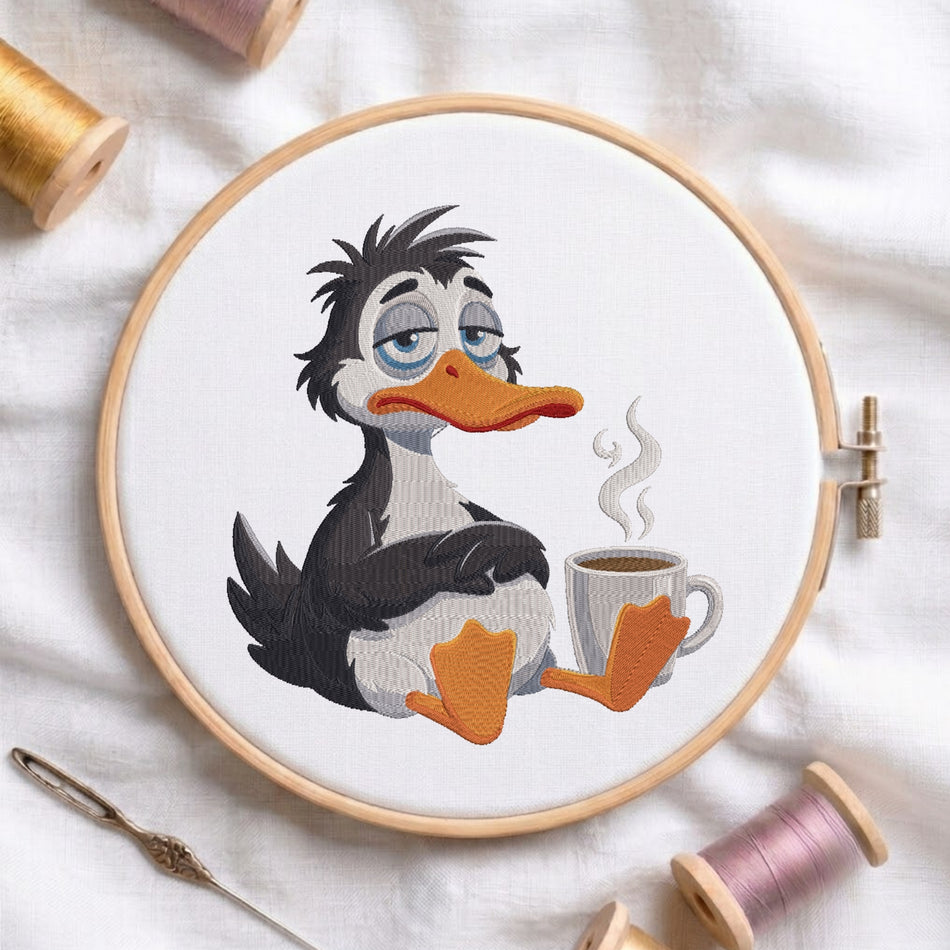 Tired duck holding a coffee cup machine embroidery design displayed inside a round wooden hoop on white linen fabric, accompanied by wooden thread spools and a needle.