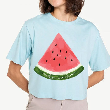 A woman modeling a light blue pastel crop top t-shirt featuring a large watercolor watermelon slice design printed on the front with the cursive text "sweet summer time".