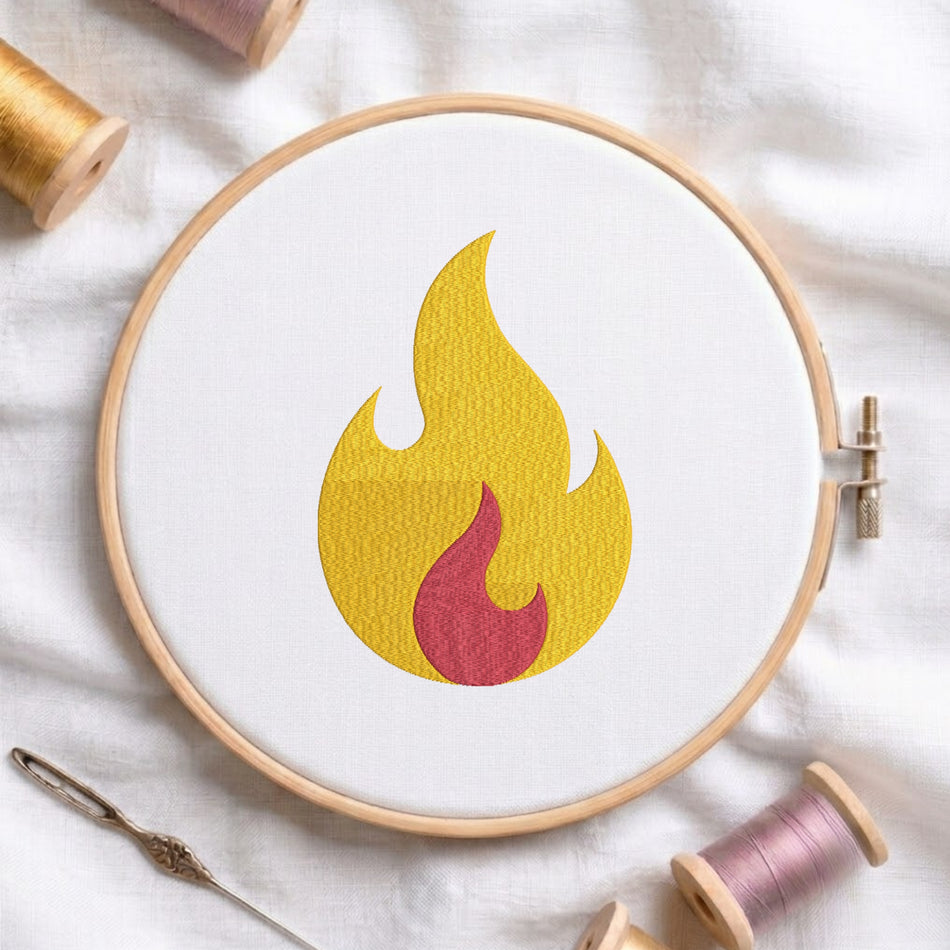 A circular embroidery hoop holding white fabric with a stylized flame motif in yellow and red, surrounded by spools of thread and a needle on a white fabric background.