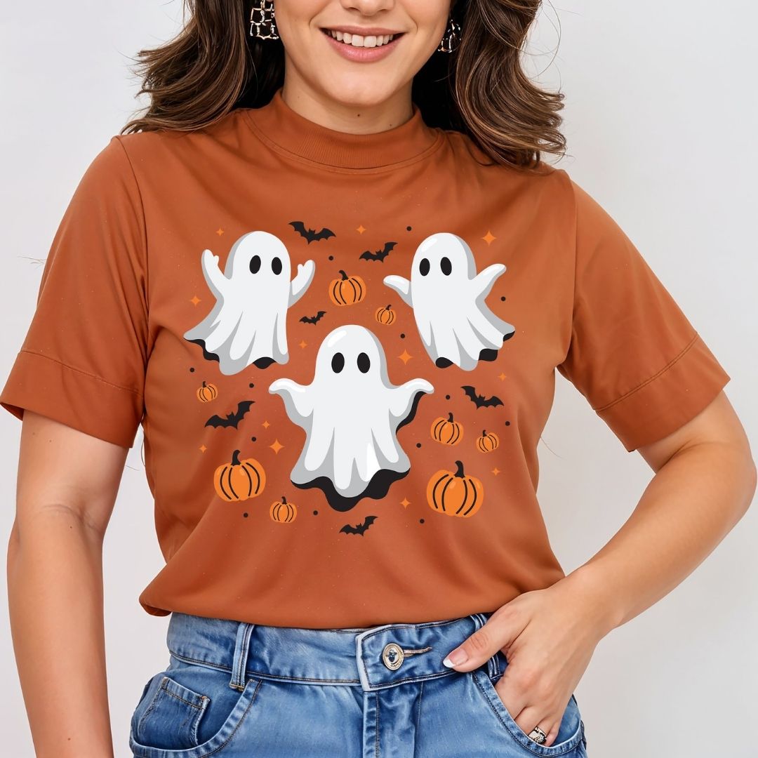 Woman wearing a rust-orange t-shirt featuring a cute Halloween ghost trio and pumpkins sublimation graphic.