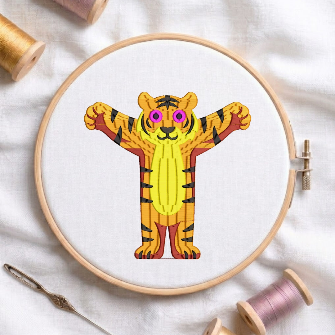 A circular embroidery hoop holding white fabric with a colorful cartoon tiger design, surrounded by spools of thread and a needle on a white fabric background.