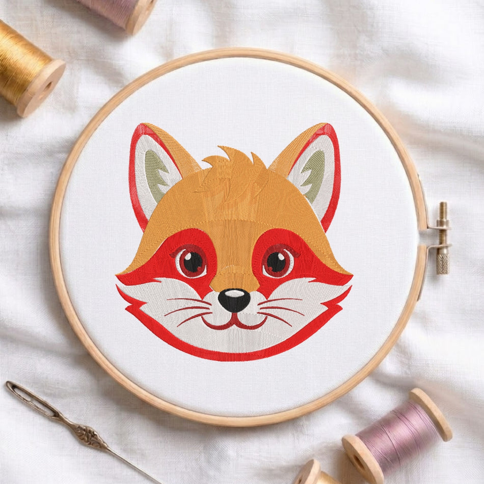 An embroidered design of a fox's face displayed in a wooden embroidery hoop, surrounded by sewing thread and a needle.