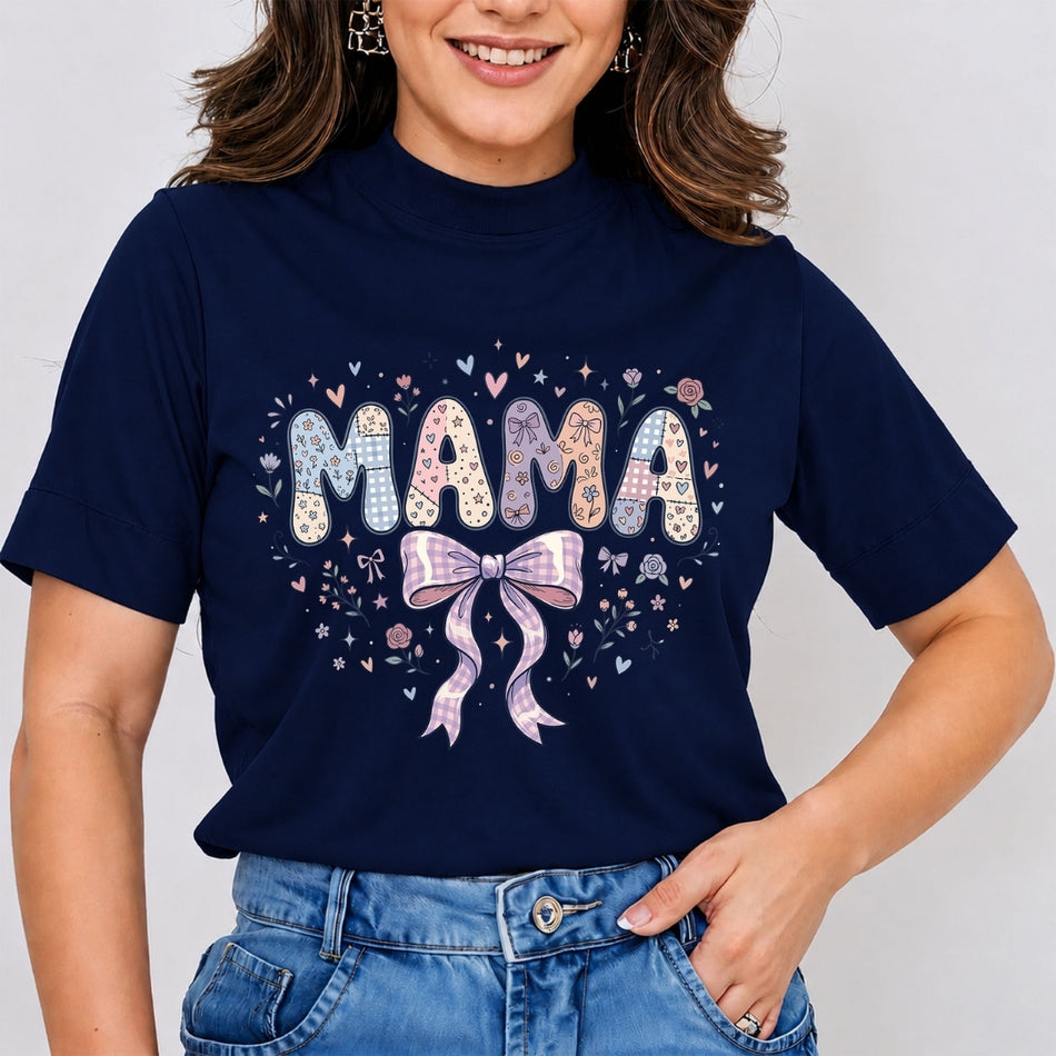 A woman wearing a navy blue short-sleeve t-shirt with a colorful graphic that reads 'MAMA' in patterned letters with a pink bow and hearts, paired with blue jeans.