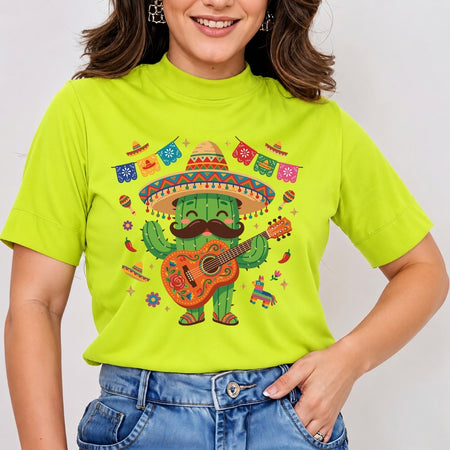 A woman wearing a bright lime green mock-neck t-shirt with a colorful graphic of a smiling cactus wearing a sombrero and playing a guitar, paired with blue jeans.