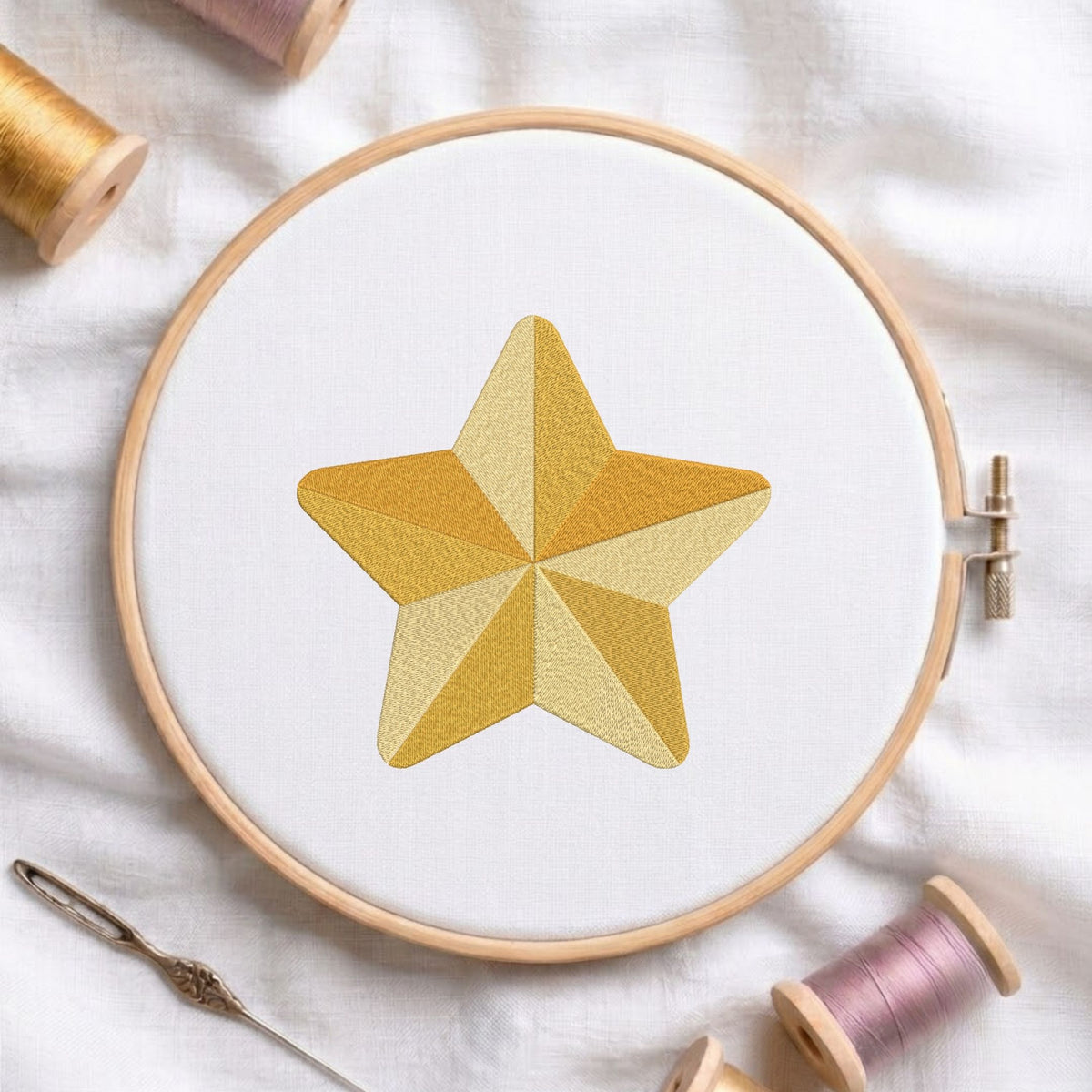 Segmented golden star machine embroidery design displayed in a wooden hoop on white fabric with thread spools and a needle