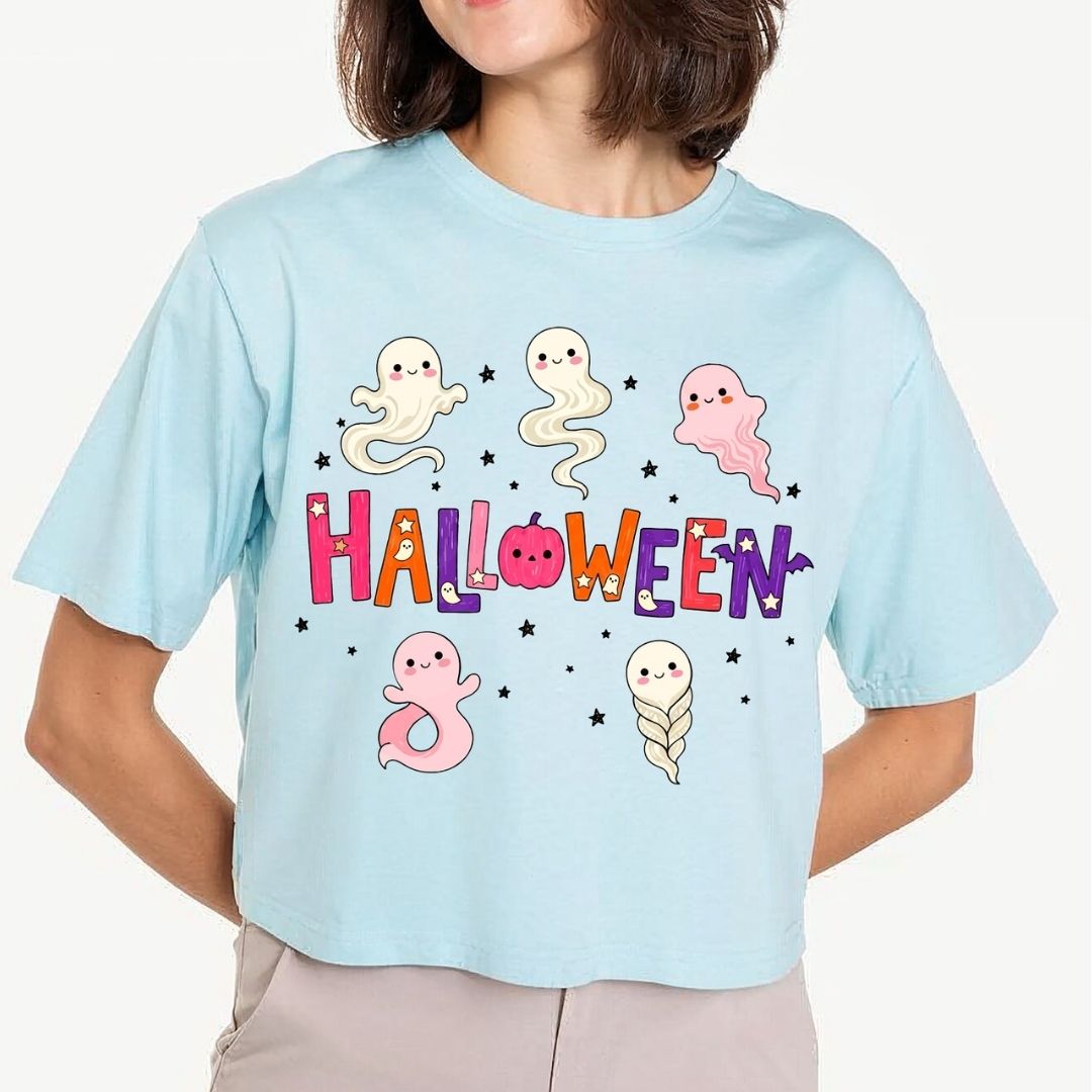 A person wearing a light blue cropped T-shirt with a colorful Halloween graphic featuring cartoon ghosts, stars, and the word 'HALLOWEEN' across the front, paired with light beige pants against a plain light background.