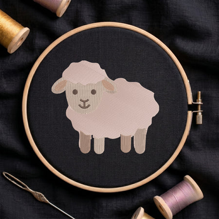 A circular embroidery hoop holding a stitched sheep design on dark fabric, surrounded by spools of thread and a needle on a dark textile background.