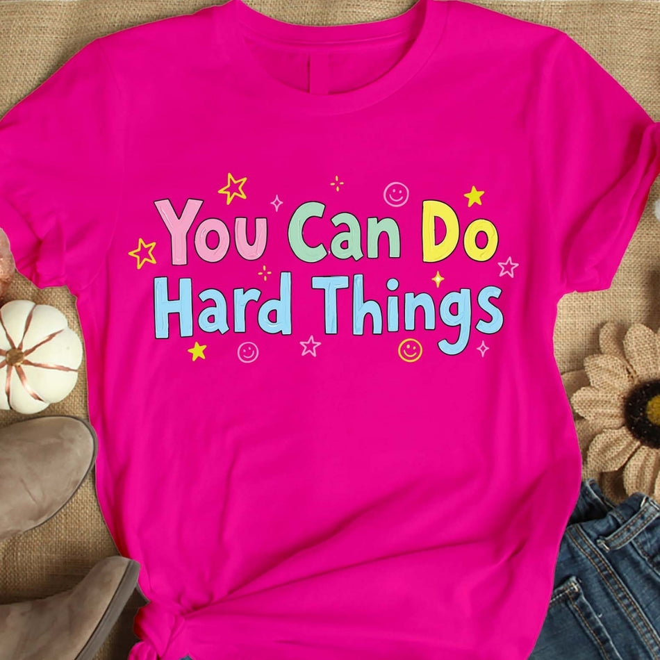 Pink t-shirt with 'You Can Do Hard Things' text on a textured surface