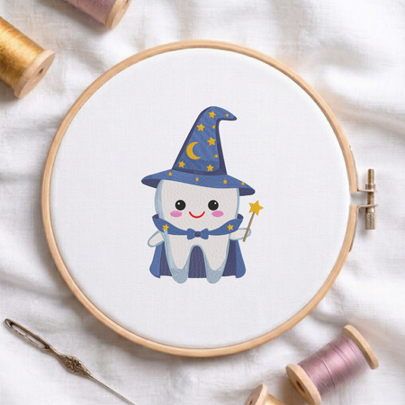 Cute wizard tooth wearing a star-patterned hat, cape, and holding a magic wand machine embroidery design shown in a wooden embroidery hoop on white fabric with thread spools and a needle