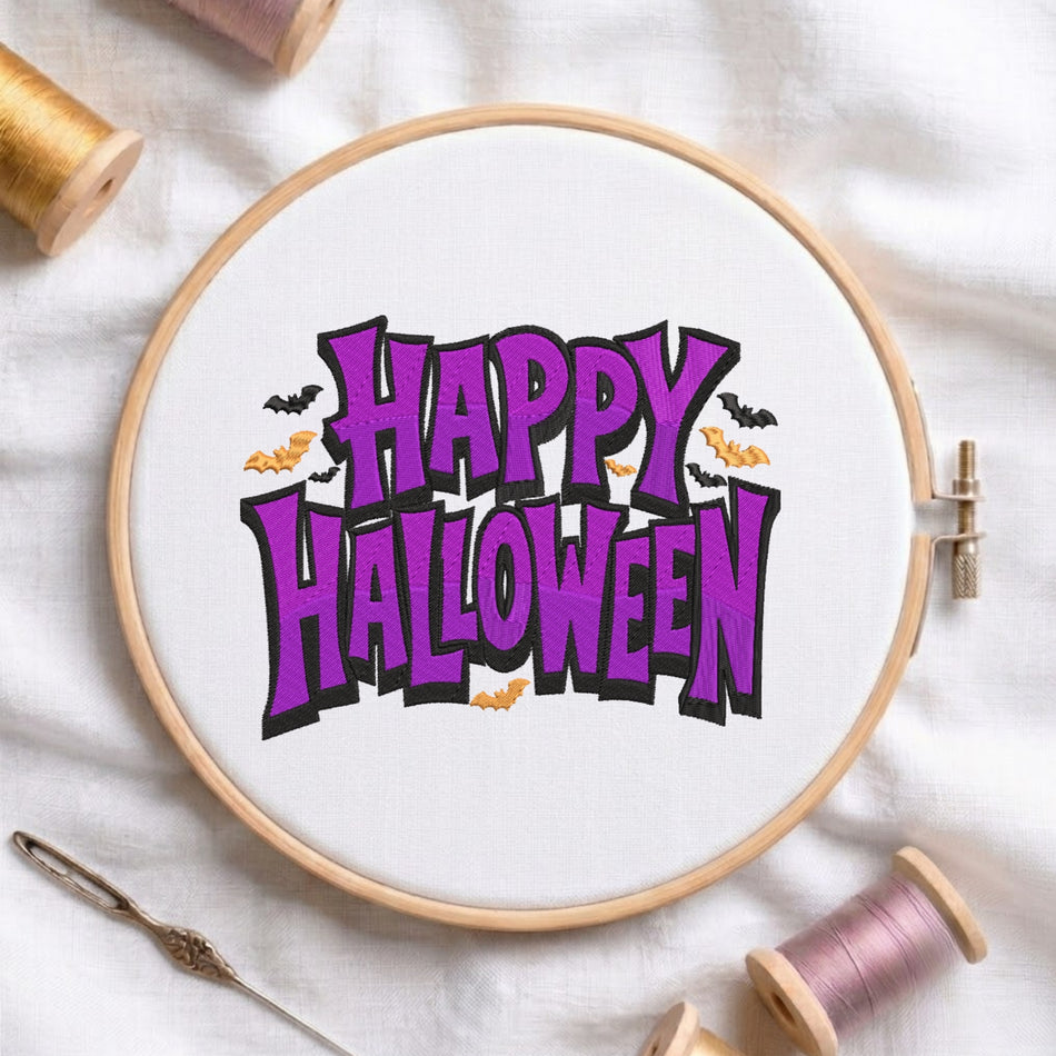 A wooden embroidery hoop holding white fabric with a colorful 'Happy Halloween' design in purple, black, and orange. Spools of thread and a needle are arranged around it on a white fabric background.