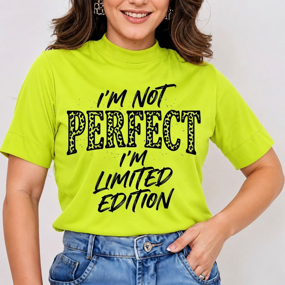 A woman wearing a bright neon yellow mock-neck t-shirt with the text 'I'M NOT PERFECT I'M LIMITED EDITION' in black and leopard-print lettering, paired with blue jeans.