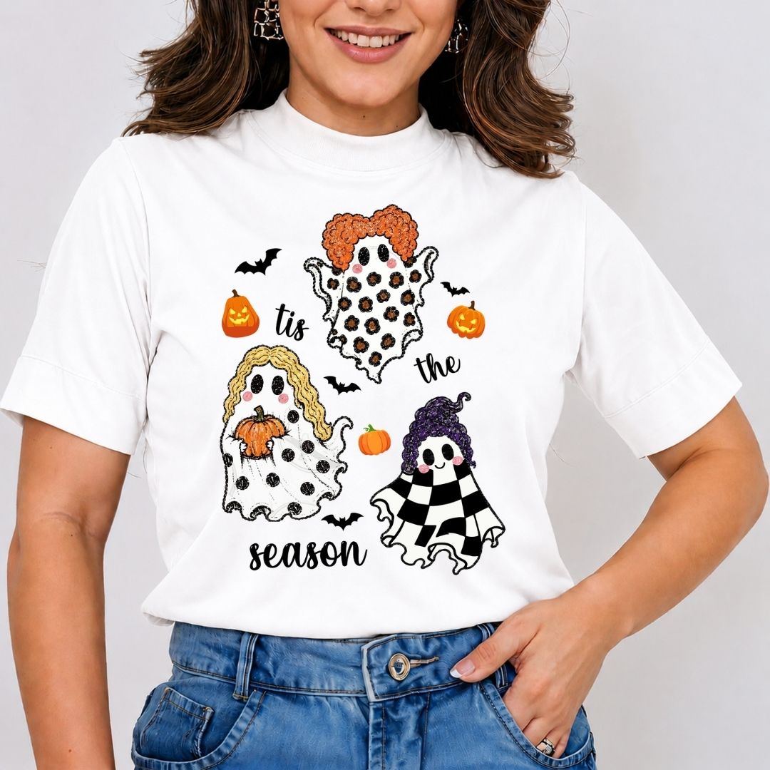 Woman wearing a white t-shirt featuring a "Tis the Season" Hocus Pocus ghost and Sanderson sisters Halloween design.