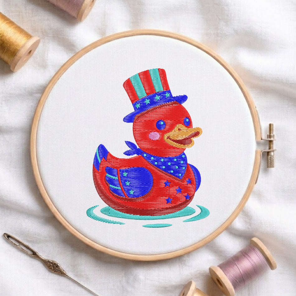 Embroidery hoop with a red duck wearing an American flag hat on a white fabric background.