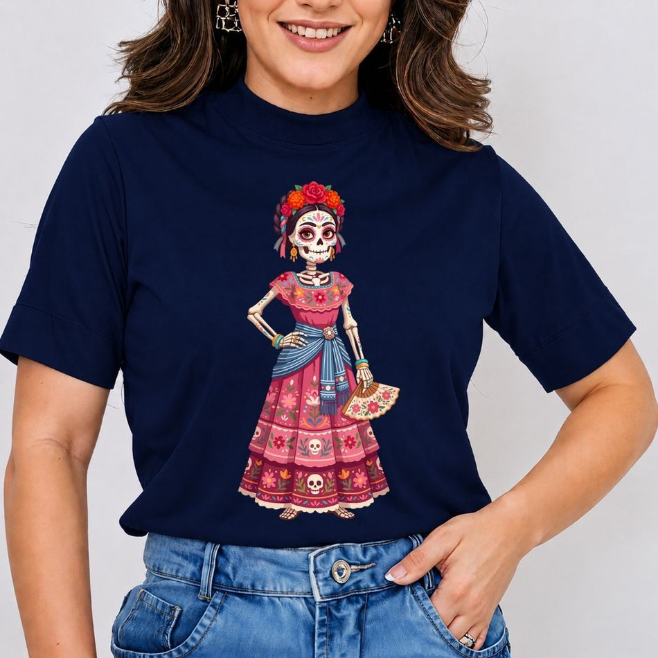 A woman wearing a navy blue mock-neck t-shirt with a colorful Day of the Dead (Dia de los Muertos) skeleton graphic on the front, paired with blue jeans.