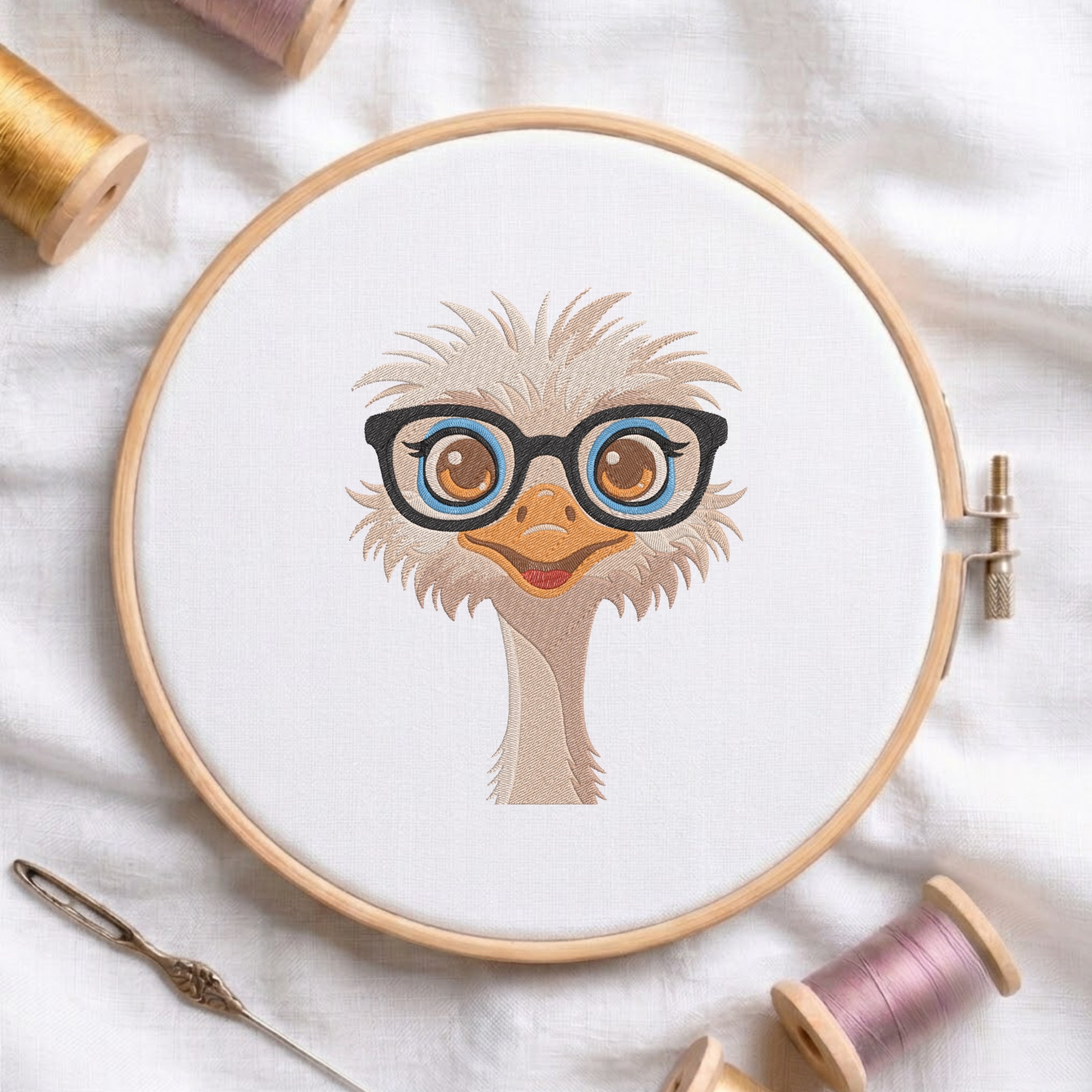 A circular embroidery hoop holding white fabric with a stylized illustration of a fluffy cream-colored bird wearing black-rimmed glasses with blue and orange details. The hoop is styled on a white fabric background with spools of thread and a needle nearby.
