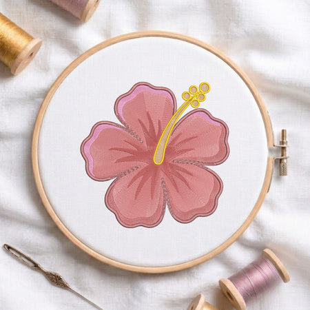 Pink hibiscus flower machine embroidery design framed in a wooden hoop with thread spools.