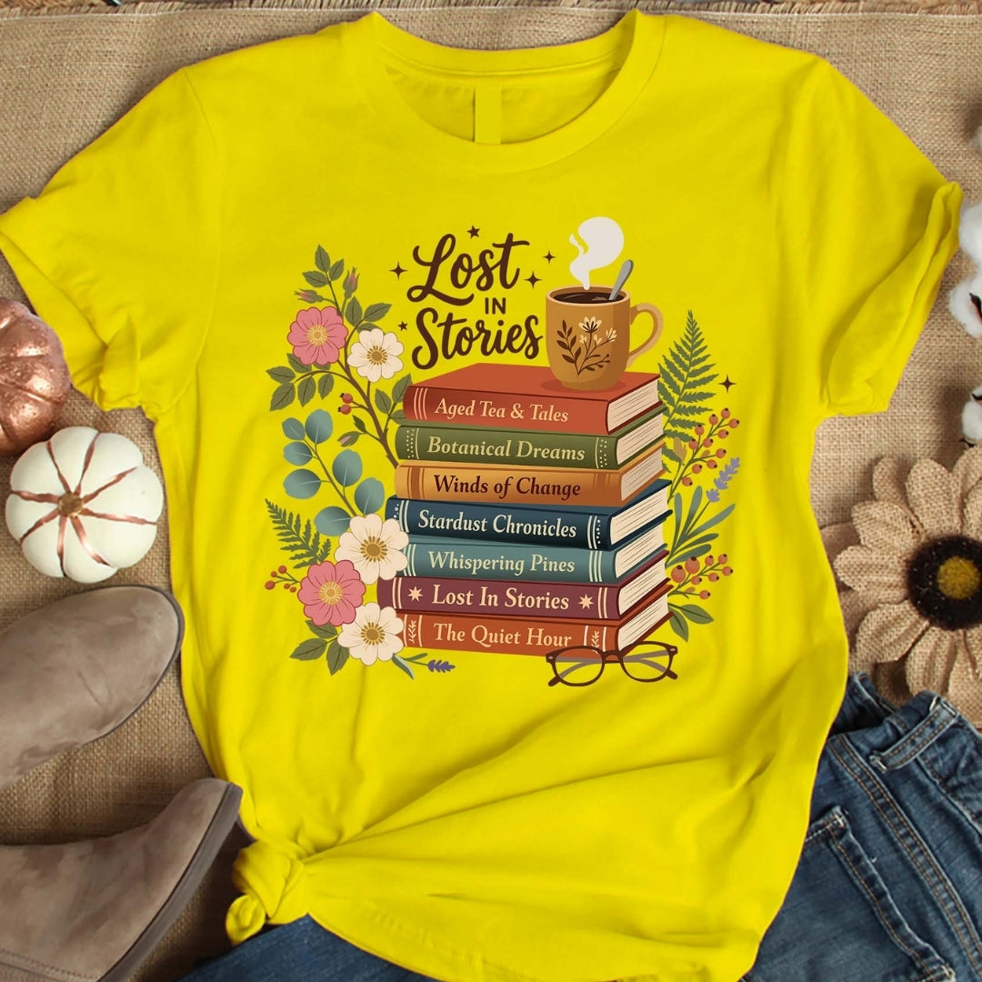 Yellow t-shirt with 'Lost in Stories' book-themed design on a textured surface.