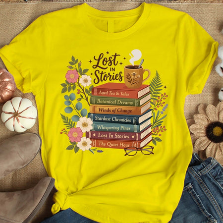 Yellow t-shirt with 'Lost in Stories' book-themed design on a textured surface.