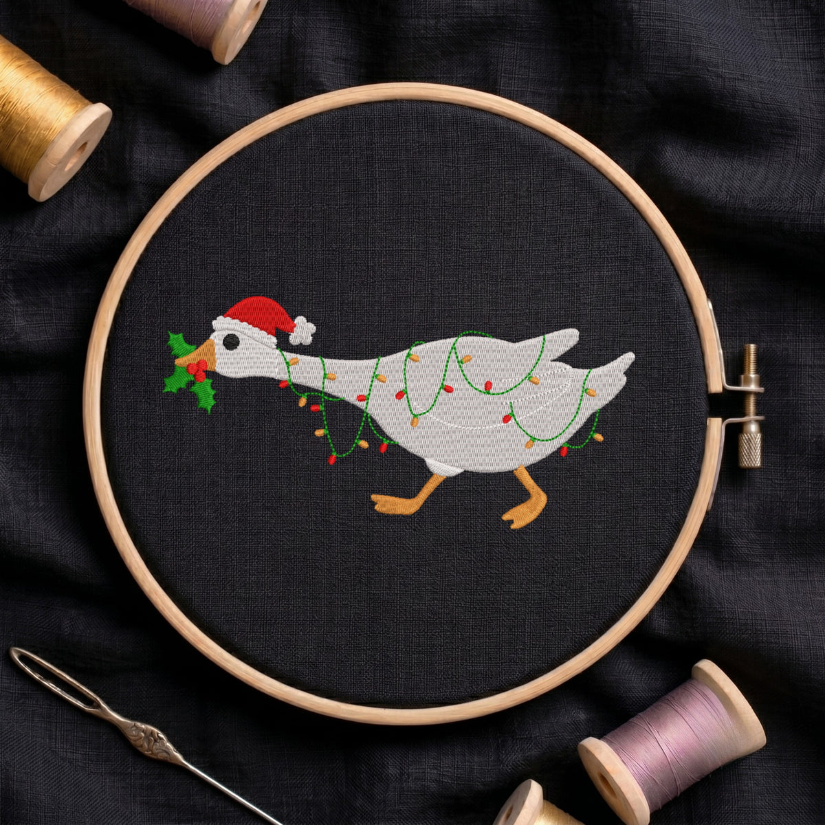 Embroidered Christmas goose wearing a Santa hat and wrapped in fairy lights in a wooden hoop.