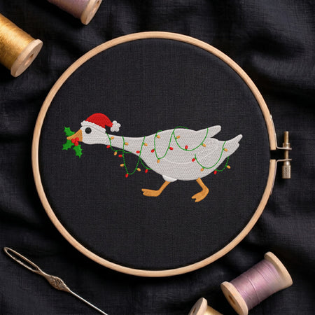 Embroidered Christmas goose wearing a Santa hat and wrapped in fairy lights in a wooden hoop.