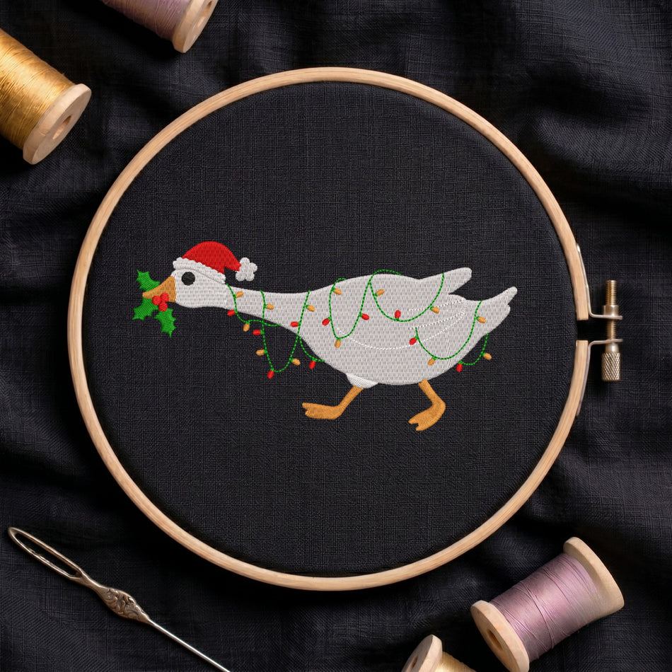 Embroidered Christmas goose wearing a Santa hat and wrapped in fairy lights in a wooden hoop.