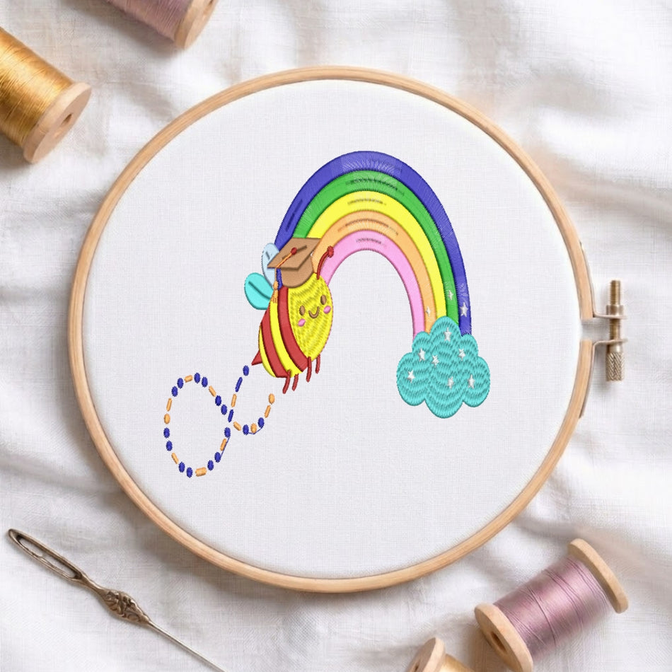 A circular embroidery hoop on white fabric holds a colorful embroidered design of a yellow bee flying on a rainbow toward a teal cloud, with spools of thread and a needle around it.