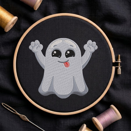 A circular embroidery hoop holding a stitched cartoon ghost design on black fabric, surrounded by spools of thread and a needle on a dark cloth background.
