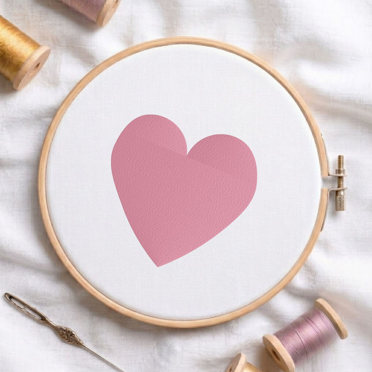 Minimalist cute heart machine embroidery design shown in a wooden embroidery hoop on white fabric with thread spools and a needle