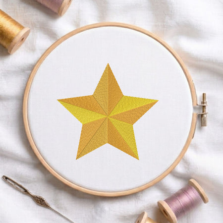 Segmented golden star machine embroidery design displayed in a wooden hoop on white fabric with thread spools and a needle