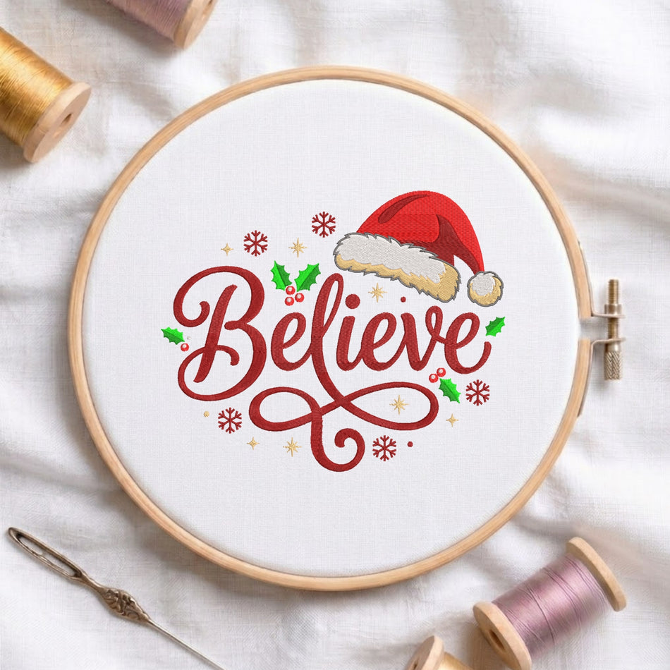 A white fabric stretched in a wooden embroidery hoop, featuring an embroidered red cursive script "Believe" decorated with a Santa hat, holly leaves, berries, and snowflakes.