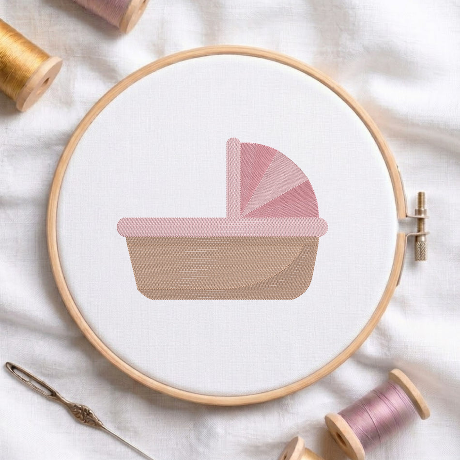 A circular embroidery hoop holding white fabric with a stitched baby carriage design in soft pink and beige. A needle and thread spools are arranged around it on a white fabric background.