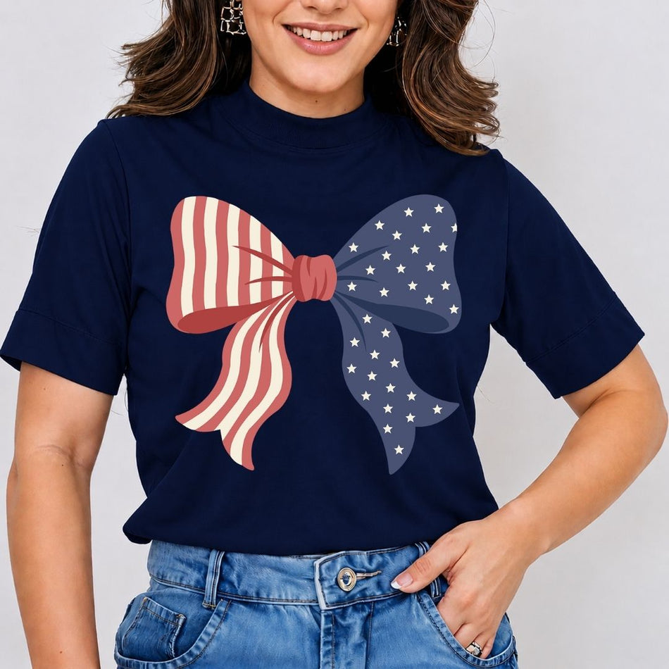 A smiling woman wearing a navy blue mock-neck t-shirt featuring a large American flag coquette bow graphic printed on the front.