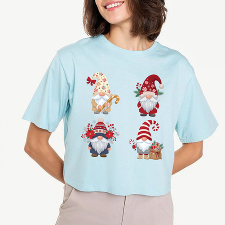 Woman wearing a light blue cropped t-shirt featuring a Christmas gnomes sublimation design with holiday hats, candy canes, and poinsettia flowers.
