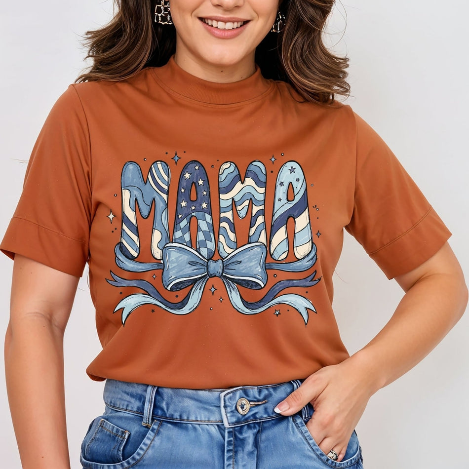 Woman wearing a rust brown mock neck t-shirt featuring a doodle-style "MAMA" graphic design filled with blue stars, checkers, and wave patterns, tied with a large blue coquette bow.