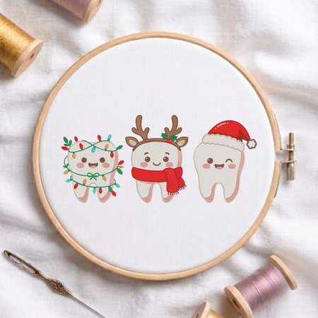 Cute Christmas teeth characters wrapped in Christmas lights, wearing reindeer antlers with a scarf, and wearing a Santa hat machine embroidery design shown in a wooden hoop on white fabric with thread spools and a needle   