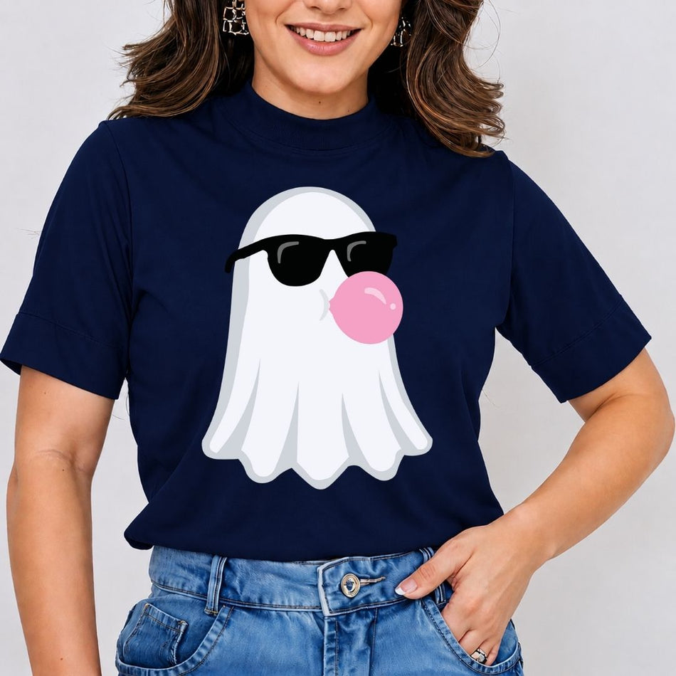 A woman wearing a navy blue t-shirt with a cartoon ghost graphic wearing black sunglasses and blowing a pink bubblegum bubble, paired with blue jeans.