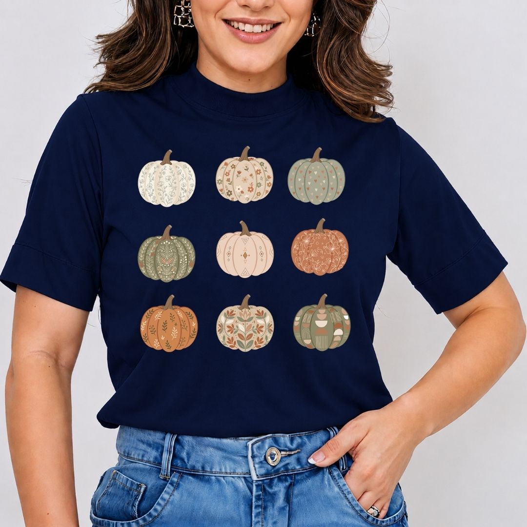 A woman wearing a navy blue short-sleeve t-shirt with a graphic of nine patterned pumpkins arranged in a 3x3 grid on the front, paired with blue jeans.