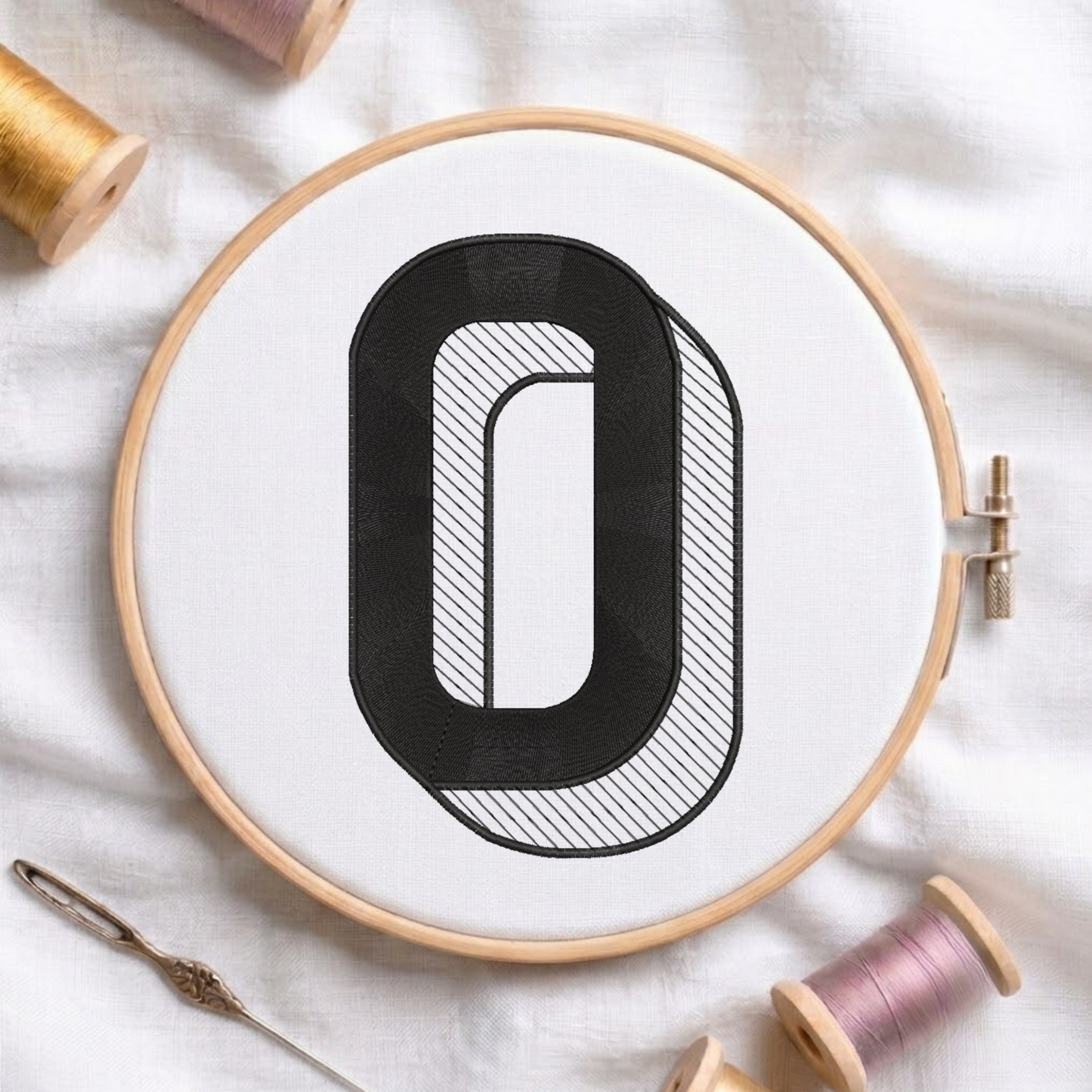 An embroidered 3D block letter "O" with striped shading texture, stitched inside a wooden hoop on white fabric with sewing threads.