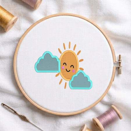 Cute smiling sun with blue clouds machine embroidery design displayed in a wooden embroidery hoop on white fabric with thread spools and a needle