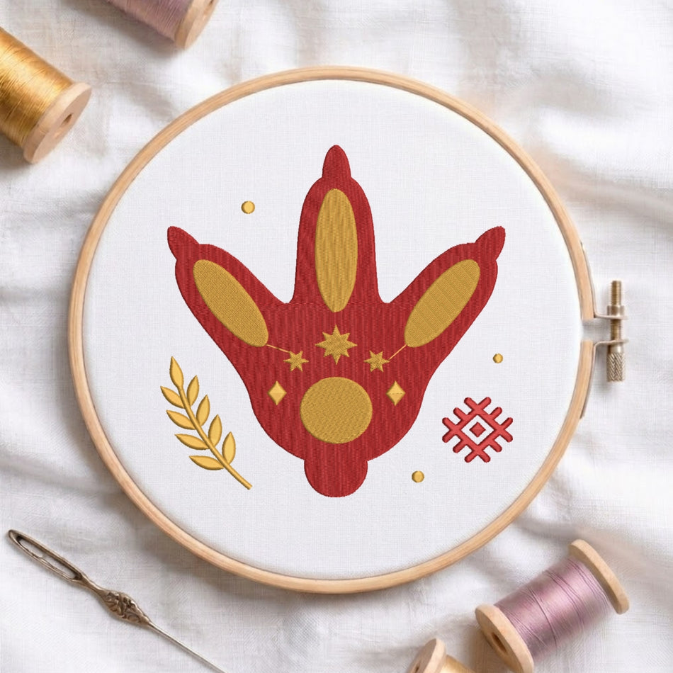 The embroidery design is presented inside a wooden embroidery hoop, shown alongside an embroidery needle and spools of thread on a white fabric surface.