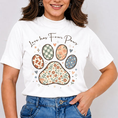 A woman wearing a white short-sleeve t-shirt with a colorful graphic of a paw print and the text 'Love has Four Paws' above it, paired with blue jeans.